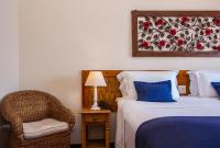 a bedroom with two beds and a chair and a picture at Barra do Piuva Porto Hotel in Ilhabela