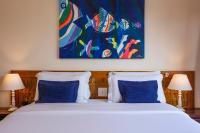 a bedroom with a bed with blue pillows and a painting at Barra do Piuva Porto Hotel in Ilhabela