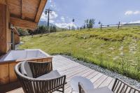 a deck with chairs and a tub and a field at Bergdorf Hotel Zaglgut in Kaprun
