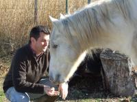 a man is feeding a white horse at Auberge des Plaines - Appartements avec terrasse in Arles