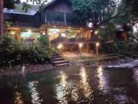 a house with a bridge over a river at night at Tree Tops River Huts in Khao Sok