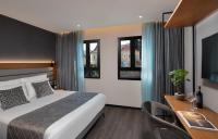 Una habitación de hotel con una cama, un escritorio y ventanas. en The Blend, en Nazaret