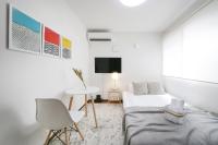 Habitación blanca con cama, mesa y TV. en アリア曳舟, en Tokio
