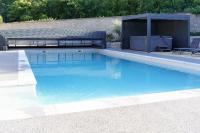 a swimming pool with blue water in a backyard at LE LODGE DU DOMAINE in Saint-Hilaire-en-Morvan