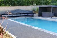a swimming pool with a bench next to a building at LE LODGE DU DOMAINE in Saint-Hilaire-en-Morvan