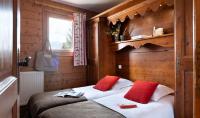 a bedroom with a bed with two red pillows at Résidence Pierre &amp; Vacances Premium Les Alpages de Chantel in Arc 1800