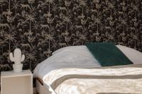 a bed with a green pillow and a black and white wallpaper at Le Longeville in Longeville-lès-Metz