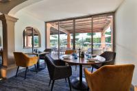 a restaurant with tables and chairs and large windows at Golf Hôtel de Valescure &amp; Spa NUXE in Saint-Raphaël