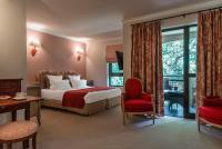 a hotel room with a bed and a red chair at Golf Hôtel de Valescure &amp; Spa NUXE in Saint-Raphaël