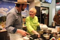 a man and a woman standing in a kitchen preparing food at Pension Spreewaldhof Leipe in Leipe