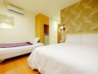 a hotel room with two beds and a vase at Green Park Commercial Hotel in Tainan