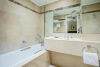 a bathroom with a tub and a sink and a mirror at Hotel Royal Saint Honore Paris Louvre in Paris