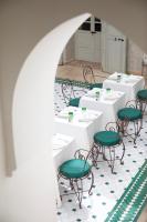 Habitación con mesas blancas y sillas verdes. en Riad Oriental Glory & Spa, en Marrakech