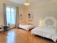 a bedroom with two beds and a table and a window at Grand studio 38m2 dans ancien palace avec piscine et place de parking privée in Aix-les-Bains