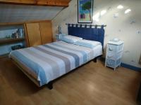 Un dormitorio con una cama grande y suelo de madera. en Les Aubretias, en Fénay