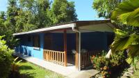 a blue house with a porch in a garden at Cabinas Caribe Luna in Cahuita