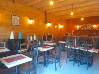 une salle à manger avec des murs en bois, des tables et des chaises dans l'établissement Le refuge, à Biollet