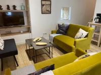 a living room with yellow couches and a tv at Le ker Maclow in Saint Malo