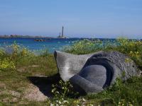 a statue sitting in the grass next to a body of water at Granite stone house with fireplace, Plouguerneau in Plouguerneau