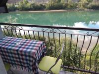 a table and a chair on a balcony overlooking a lake at Vikendica pored Drine Foča in Handići