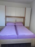 a bedroom with two beds with purple sheets and white cabinets at Apartments with a parking space Lopar, Rab - 17103 in Lopar