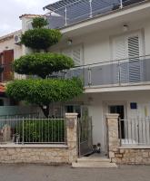 a house with a gate and a tree in front of it at Rooms &amp; Apartments Barišić in Mlini