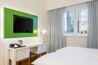 a hotel room with two beds and a flat screen tv at NH Frankfurt Messe in Frankfurt