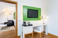 a room with a desk and a tv on a wall at NH Frankfurt Messe in Frankfurt