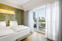 a bedroom with a bed and a large window at NH Frankfurt Messe in Frankfurt