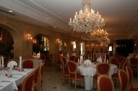 een eetkamer met witte tafels en stoelen en een kroonluchter bij Servotel Castagniers in Castagniers