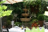 een tafel met stoelen en een fontein in een tuin bij Servotel Castagniers in Castagniers