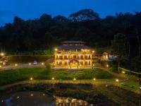 a large building at night with a pond at The Hosteller Coorg Rainforest, Madikeri in Madikeri