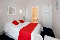 a bedroom with a red and white bed and a bathroom at Hotel Biney in Rodez