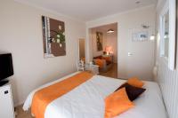 a bedroom with a large bed with an orange blanket at Hotel Biney in Rodez