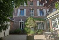 a brick building with a table in front of it at Maison de maître, un coin de verdure en hyper centre in Lisieux