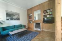 a living room with a blue couch and a tv at Maison de maître, un coin de verdure en hyper centre in Lisieux