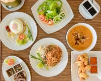 a wooden table with plates of food on it at Tinidee Golf Resort Phuket in Kathu