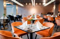 Un comedor con sillas y mesas naranjas con servilletas. en Hunguest Bük - ex Répce és Répce Gold, en Bük