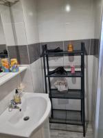 a bathroom with a white sink and a black shelf at T1 meublé in Saint-Chamond