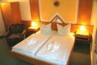 a bedroom with a bed with white sheets and two lamps at Hotel Asterra in Saalfeld