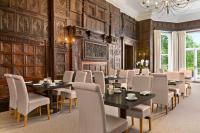 a dining room with tables and chairs and a chandelier at Trenython Manor Resort in Fowey