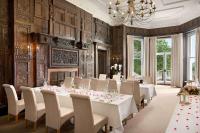 a dining room with white tables and chairs and a chandelier at Trenython Manor Resort in Fowey