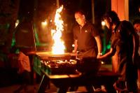 Um homem e uma mulher em pé ao lado de uma churrasqueira com fogo. em Horizon KiteSurfing Beach Resort em Kalpitiya