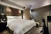 a bedroom with a large white bed and a chair at The Tango Hotel Taipei FuHsing in Taipei