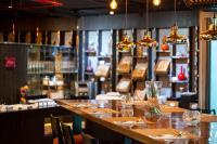 een restaurant met een lange bar met tafels en stoelen bij Maitria Mode Sukhumvit 15 Bangkok - A Chatrium Collection in Bangkok