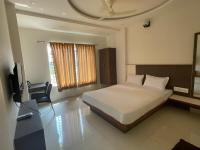 a bedroom with a bed and a desk and a television at DC comforts in Chikmagalūr