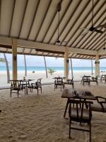 un restaurante en la playa con mesas y sillas en Hondaafushi Island Resort, en Vaikaradhoo
