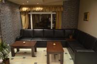 Un sofá de cuero negro en una sala de estar con dos mesas. en Garni Hotel Lion, en Jagodina