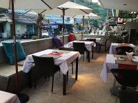 un ristorante con tavoli e sedie con tavoli e ombrelloni bianchi di Kata Beach Studio Phuket a Kata Beach