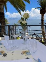 a table with glasses and a vase with flowers on it at Hotel Villa Giulia in Gargnano